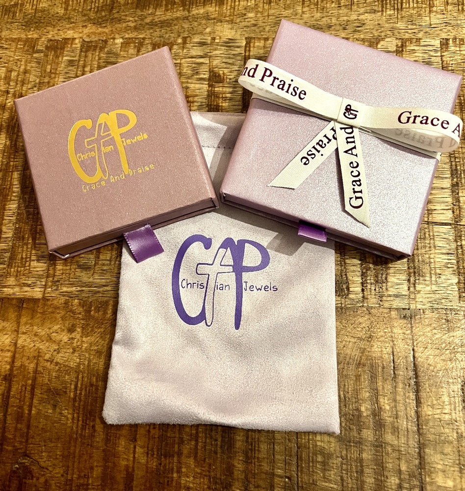 Drie sieradendoosjes en een stoffen zakje met Grace And Praise “Christian Jewels” op een gouden houten achtergrond.