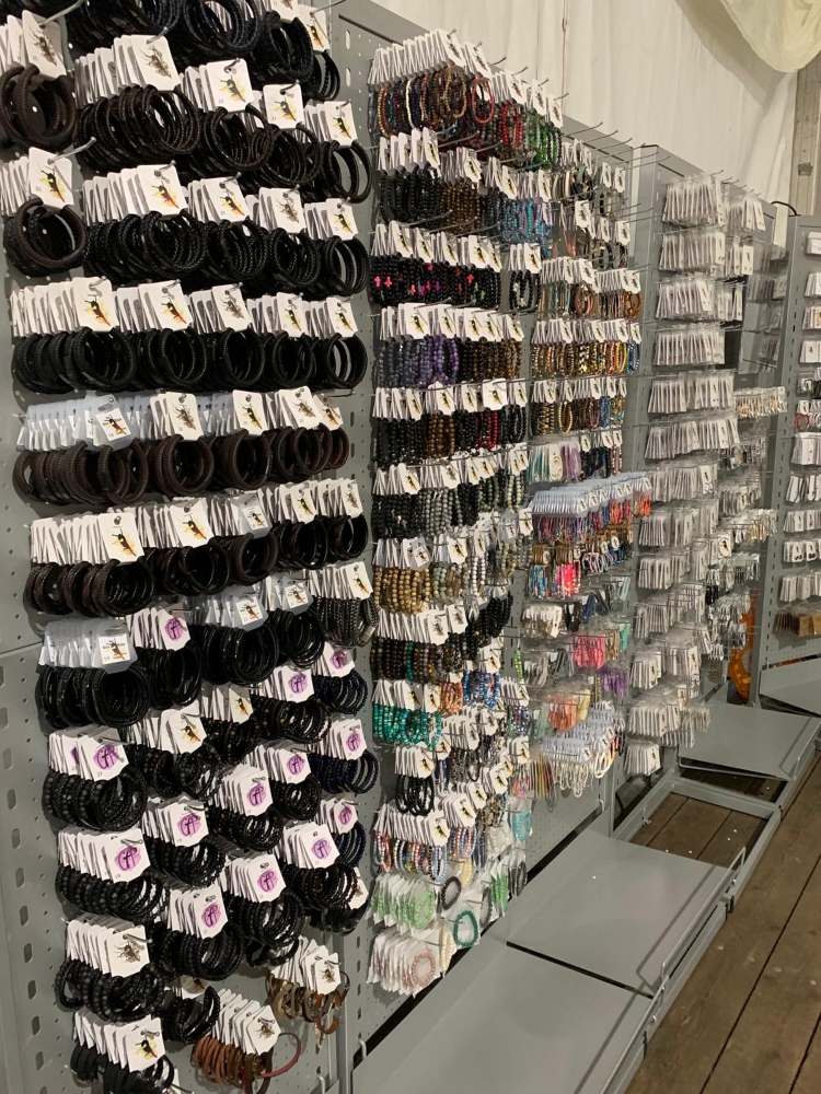 Rek met rijen armbanden van Grace And Praise in verschillende kleuren, verpakt op hangkaartjes.