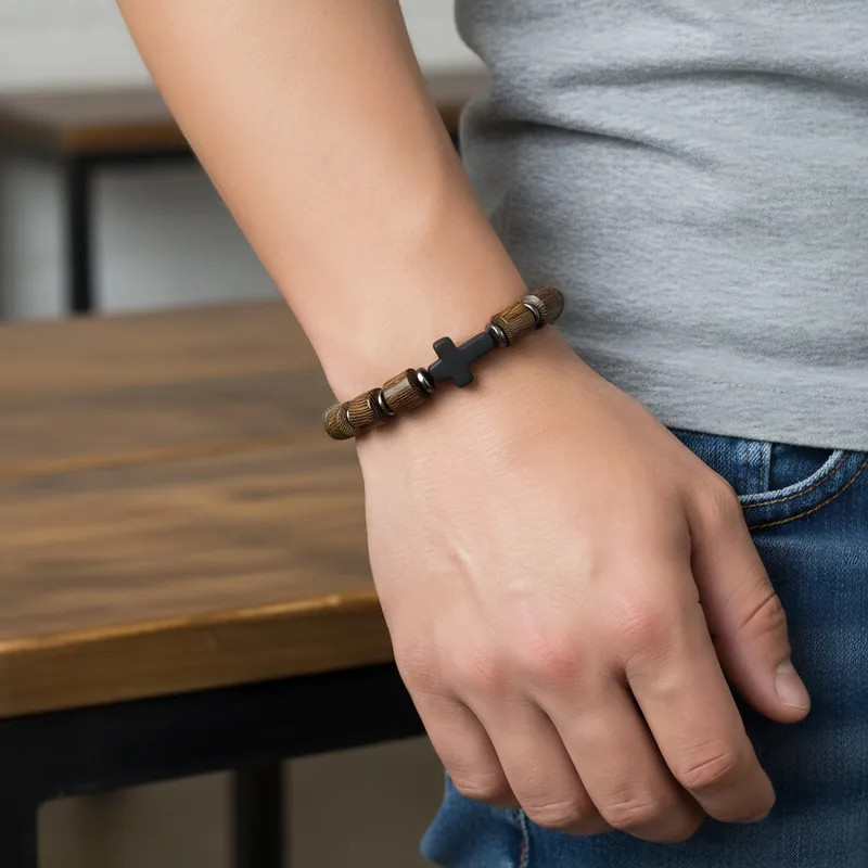 Hand met armband van kralen en metalen schakels, van Grace And Praise,gedragen bij casual kleding in een lichte kamer.