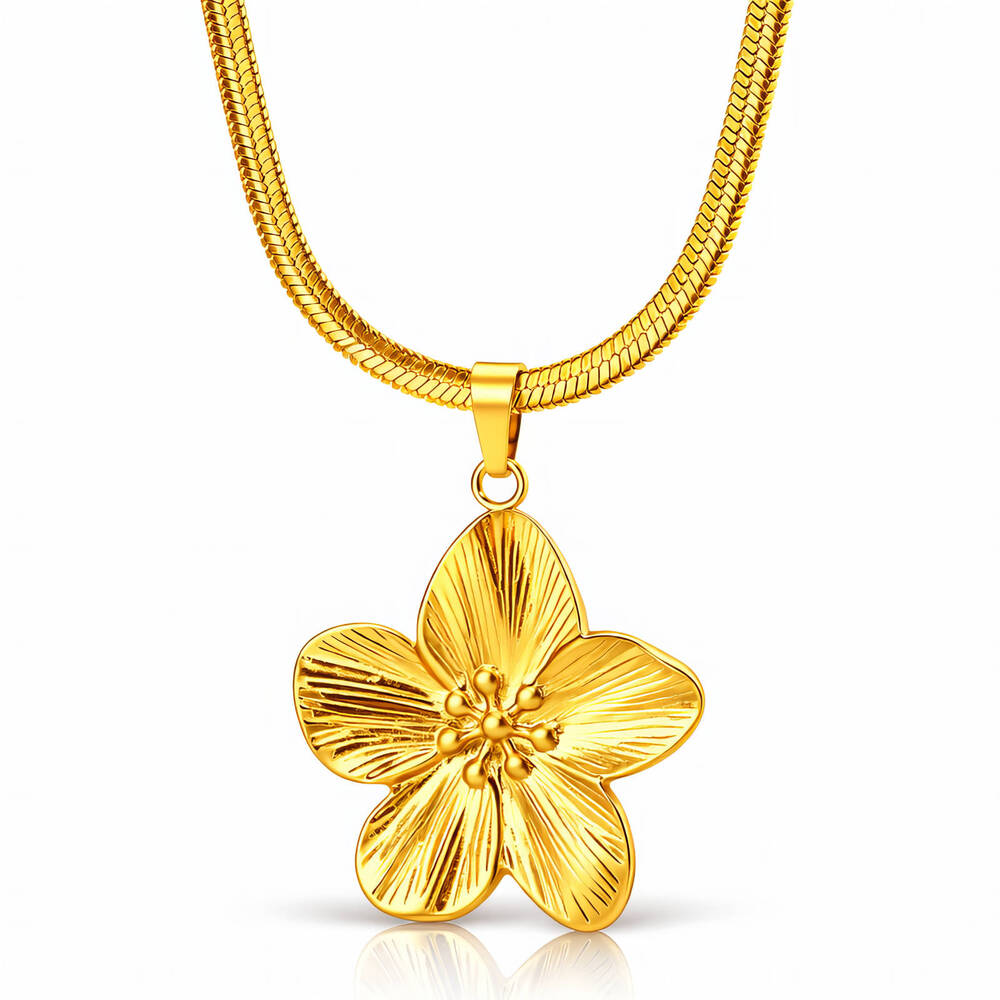 Gouden ketting met platte schakelband en hangend bloemvormig bedeltje op witte achtergrond.